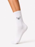 White knee-high/crew sock on a leg with a small black wing logo on the side, ribbed cuff, plain white design.