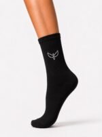 Black ribbed crew sock worn on a leg, with a small white leaf-style logo near the ankle/instep area